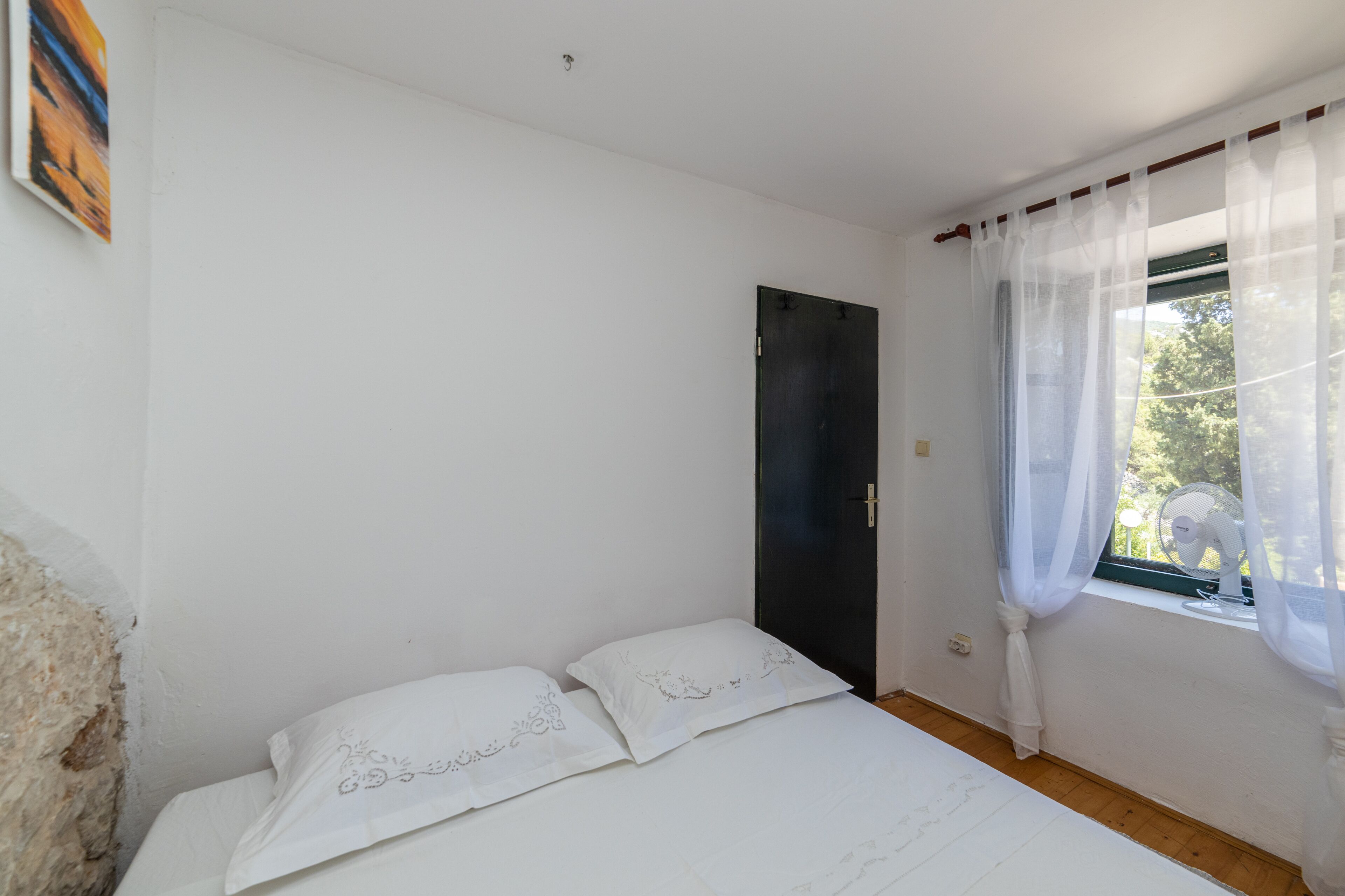 A simple room with a bed, a door, and a window with curtains.