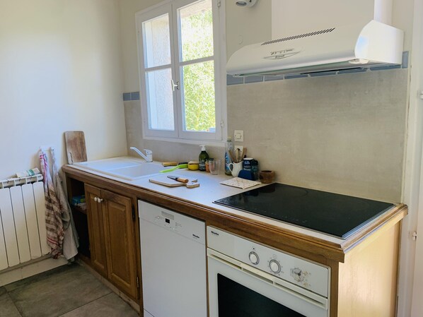 Una cocina con lavavajillas, estufa y una ventana sobre el fregadero.