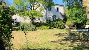 A house with a garden, surrounded by trees and greenery.