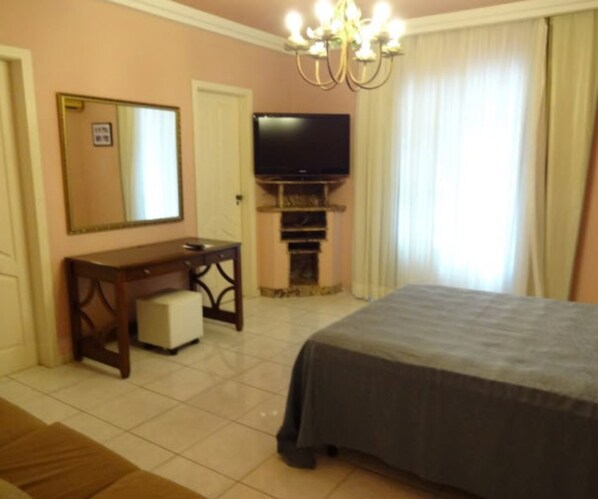 A bedroom with a bed, a television, a desk, and a mirror. - Villa Norma Suites (Vitoria)