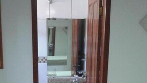 A narrow doorway leading to a bathroom with a sink, mirror, and toilet visible. - Villa Norma Suites (Vitoria)