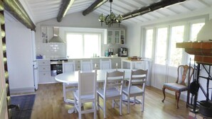 A spacious kitchen with white cabinetry, a dining table with chairs, and a chandelier.