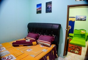 Un dormitorio con una cama, almohadas, una silla verde y dos cuadros colgados en la pared.