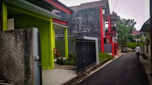 Un barrio residencial con casas de fachadas verdes y rojas intensas, una entrada protegida por un portón y una calle estrecha.