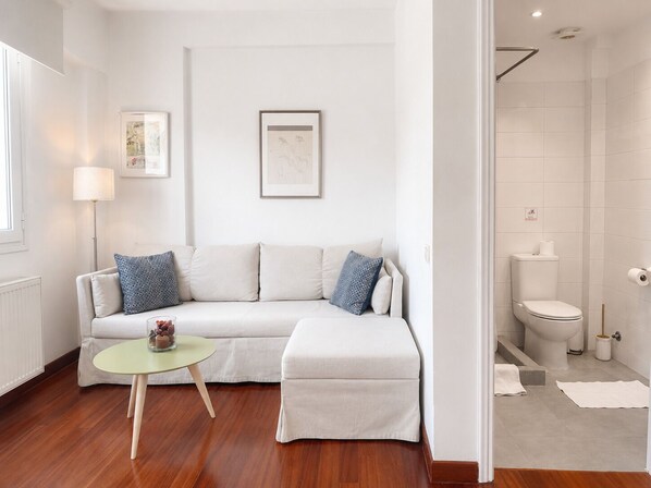 A modern living room with a sofa, a small round table, and a floor lamp.