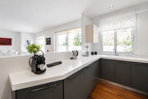 Een moderne keuken met een koffieapparaat, waterkoker en koffiemachine op het aanrecht.