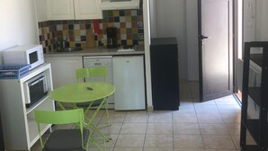 Une cuisine de taille réduite avec un coin repas, un ventilateur de plafond et un réfrigérateur.