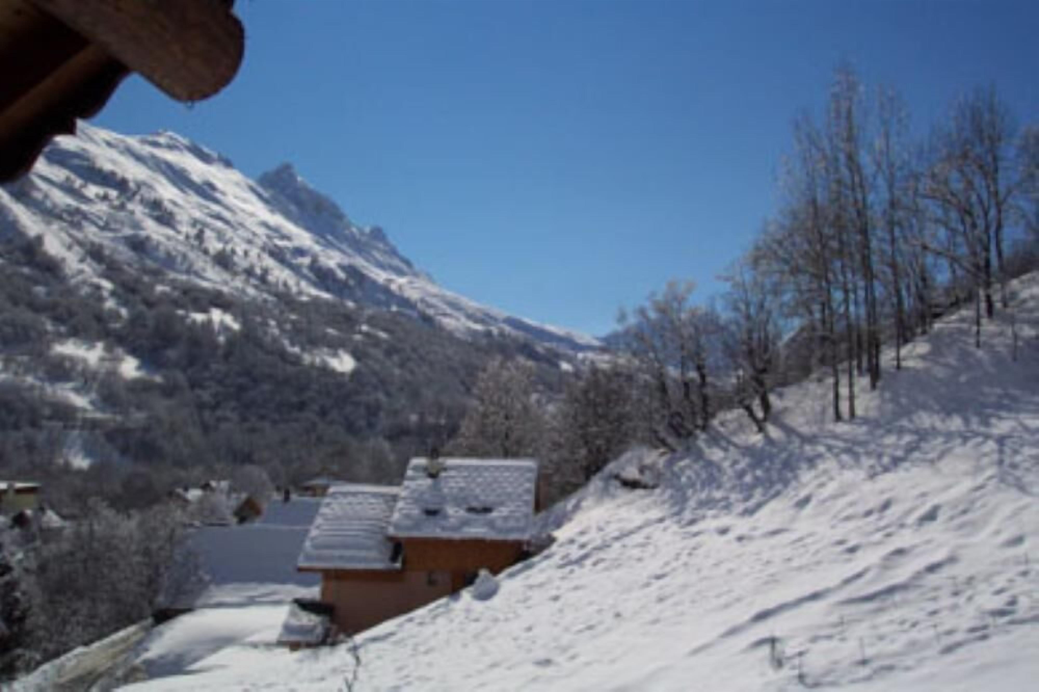 A snow-covered mountain landscape with a building in the foreground.