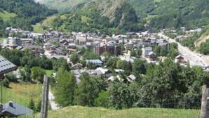 Eine kleine Stadt liegt eingebettet in ein Tal, umgeben von üppigen grünen Hügeln und Bergen, mit einer Mischung aus traditioneller und moderner Architektur.