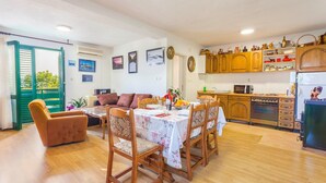 A cozy dining area with a wooden table and chairs, a sofa, and a kitchen with wooden cabinets and a refrigerator. - Villa Paradise village in Tucepi, private pool (Tucepi)