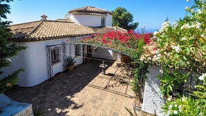 A courtyard with a tiled roof, potted plants, and flowering bushes. - Luxury villa stunning views, private heatable pool (Salobreña)