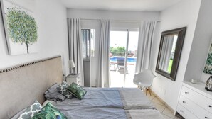 A bedroom with a bed, a dresser, a chair, and a view of an outdoor swimming pool. - Luxury villa stunning views, private heatable pool (Salobreña)