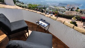 A terrace with two black cushioned chairs, a small table with a glass, and a view of the sea and mountains. - Luxury villa stunning views, private heatable pool (Salobreña)