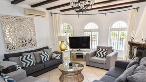 A modern living room with a grey sofa set, a glass coffee table, and a TV. - Luxury villa stunning views, private heatable pool (Salobreña)