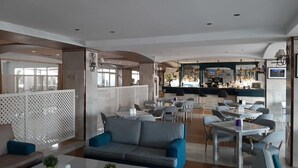 En moderne hotellobby med barområde, siddepladser og en dekorativ rumdeler.