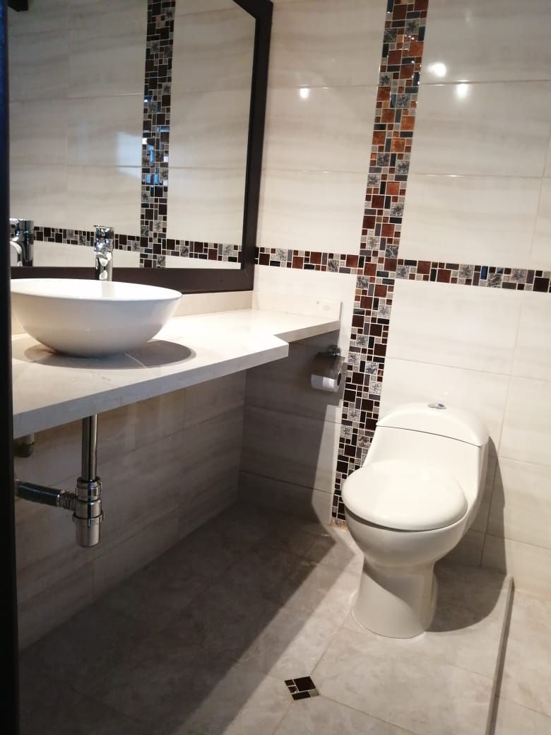 Ein modernes Badezimmer mit einem weißen Waschbecken, einer Toilette und einer gefliesten Rückwand.
