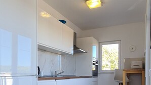 A modern kitchen with white cabinets, a marble countertop, and a built-in oven. - Apartment Penthouse by the sea - Vrboska - Island Hvar (Vrboska)