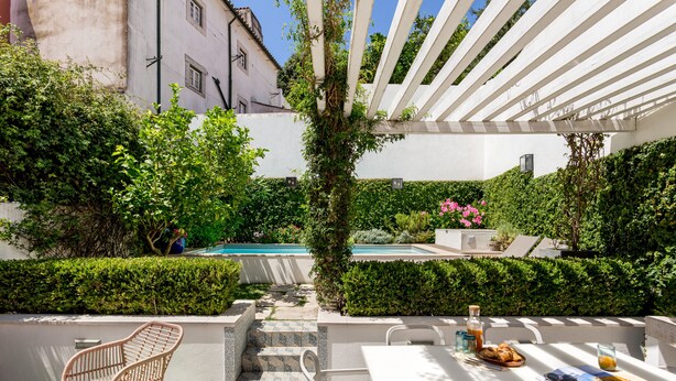 An outdoor patio with a pool, white furniture, and a pergola. - By the Castle | LUXURIOUS, PRIVATE GARDEN & HEATED SWIMMING POOL (Lisboa)