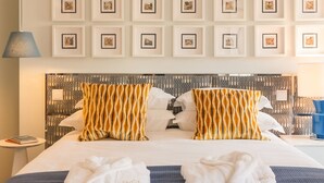 A hotel room with a large bed, two pillows with a striped pattern, two towels, and a pair of slippers on a woven mat. - By the Castle | LUXURIOUS, PRIVATE GARDEN & HEATED SWIMMING POOL (Lisboa)