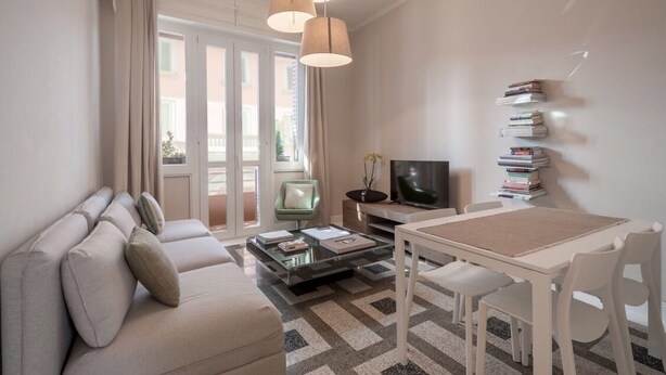 Ein modernes Wohnzimmer mit einer Couch, einem Couchtisch, einem Fernseher und Bücherregalen.