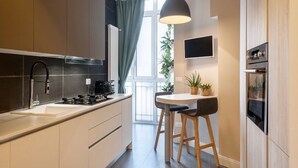 Eine moderne Küche mit einem großen Fenster, einer Essecke mit Hockern und einem eingebauten Backofen.