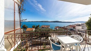 A balcony with a table and chairs, overlooking a coastal town and a body of water. - Nice apartment in Seget Donji with house sea view (Seget Donji)