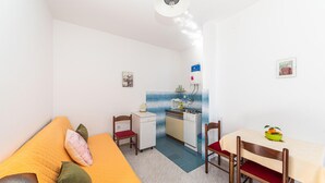 A compact room with a bed, a small kitchenette, a dining table, and a chair. - Nice apartment in Seget Donji with house sea view (Seget Donji)