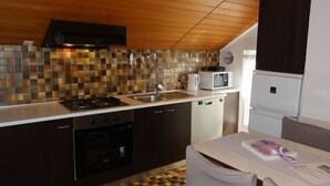 A modern kitchen with a tiled backsplash, stainless steel appliances, and a wooden ceiling. - Apartment Mira by Interhome (Vir)