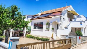 A white building with a tiled roof, a balcony, and a gate. - Apartment Mira by Interhome (Vir)