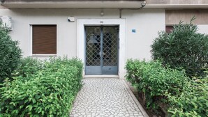 Une entrée d’immeuble avec une plaque portant le numéro 90, un portail en métal et un chemin dallé.