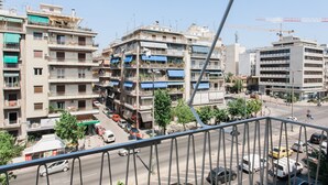 Un immeuble à plusieurs étages doté de balcons, donnant sur la rue, avec une grue de construction visible à l’arrière-plan.