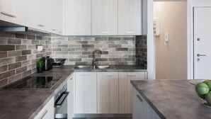 Une cuisine moderne dotée d’une cuisinière intégrée, d’un évier en acier inoxydable et de meubles de rangement en bois clair.