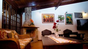 A cozy living room with a fireplace, a sofa, a coffee table, and a TV. - Pousada Martinez (Valenca)