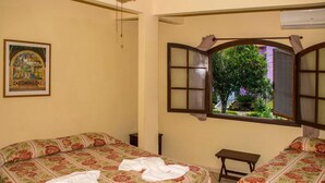 A hotel room with two beds, a window with a view of greenery, and a painting on the wall. - Pousada Martinez (Valenca)