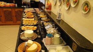 A buffet with various food items including cheese, bread, and milk. - Pousada Martinez (Valenca)