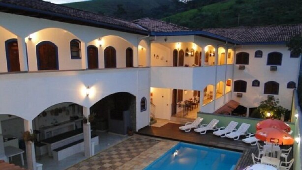 A hotel with a swimming pool, sun loungers, and a covered patio area. - Pousada Martinez (Valenca)