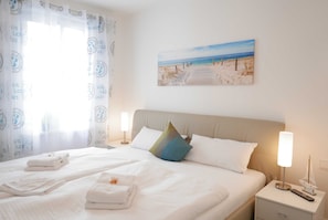 Cama bem arrumada com lençóis brancos, um travesseiro e mesa de cabeceira com abajur e um objeto decorativo.