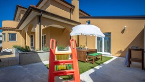A patio with a red chair, a white umbrella, and a wooden table with a green cushion. - Gorgeous apartment in Smrika with WiFi (Smrika)
