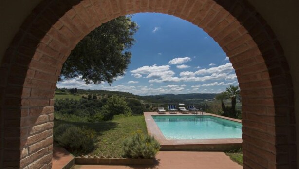 Zona de piscina con una vista despejada del paisaje a través de una estructura de ladrillo en arco.