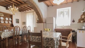 Un comedor con sillas y mesas de madera, un candelabro y una cocina al fondo.
