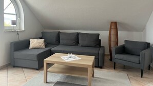 A modern living room with a grey sectional sofa, a wooden coffee table, and a tall bamboo lamp.