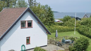 Une maison blanche avec un toit rouge, une terrasse avec des meubles d’extérieur et une vue sur la mer.
