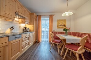 Una cocina con armarios de madera, una mesa de comedor con sillas, un banco y una lámpara colgante.