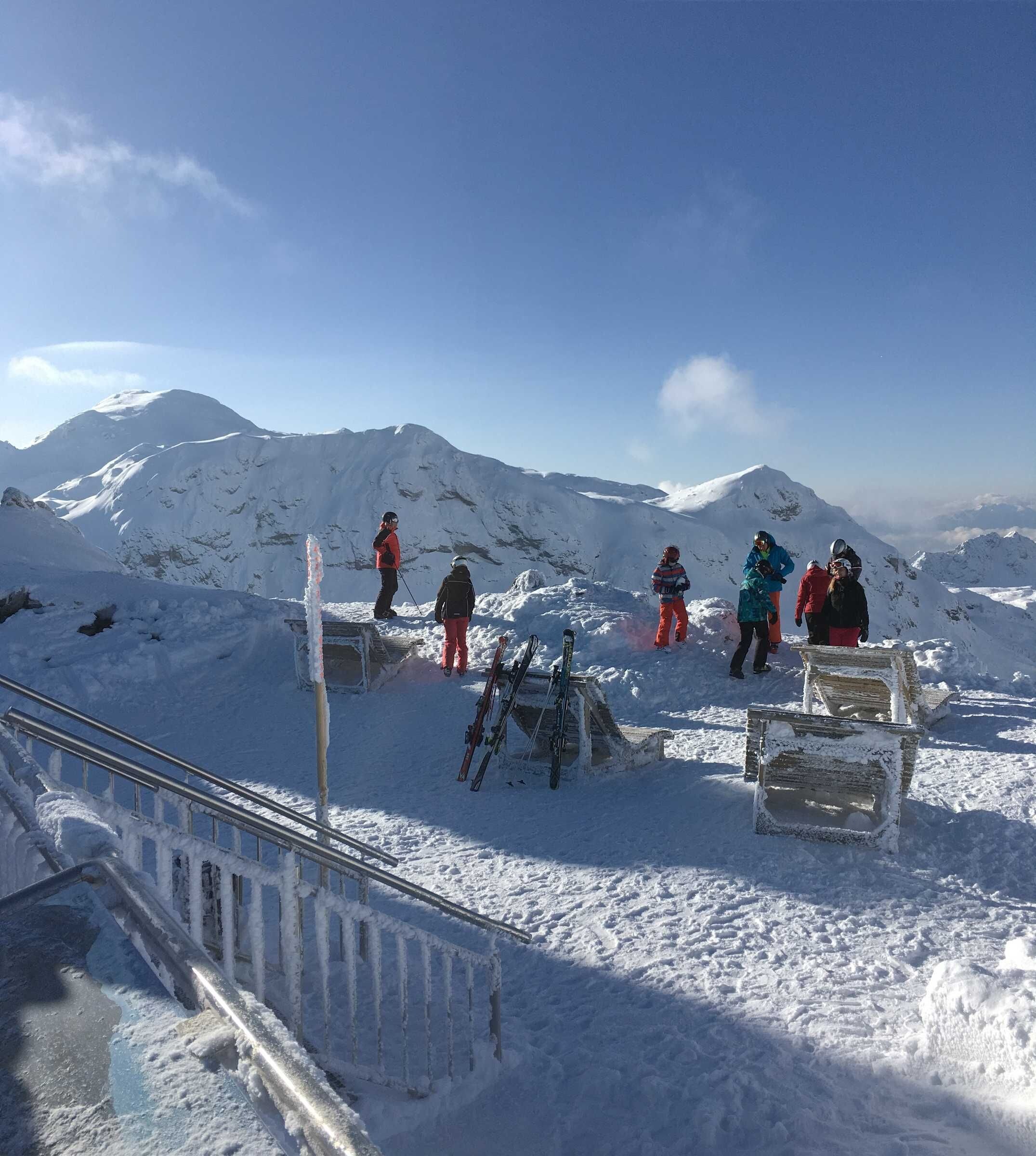 A snowy mountain landscape with skiers and a metal staircase.