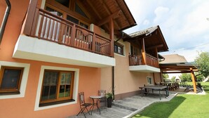 A two-story building with balconies, outdoor seating, and a covered patio area. - Apartment Dobratsch - Apartments Umfahrer Nassfeld (Tröpolach)