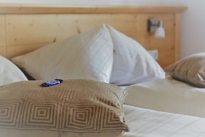 A bed with patterned pillows and a wooden headboard. - Apartment Dobratsch - Apartments Umfahrer Nassfeld (Tröpolach)