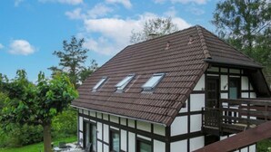 Ett traditionellt hus med korsvirkesfasad, ett sluttande tak, två takfönster och en träveranda.