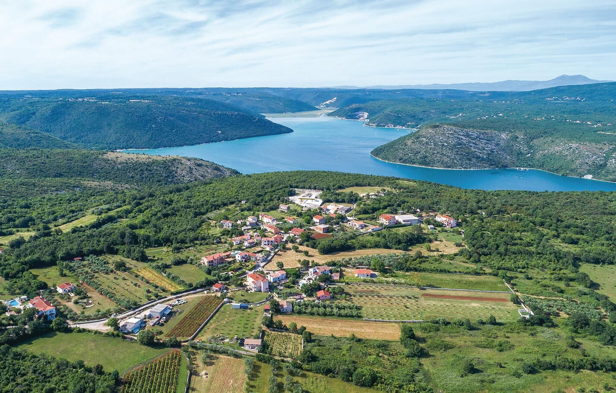 Ein Luftbild eines Küstdorfes mit Häusern, Feldern und einer großen Wasserfläche.