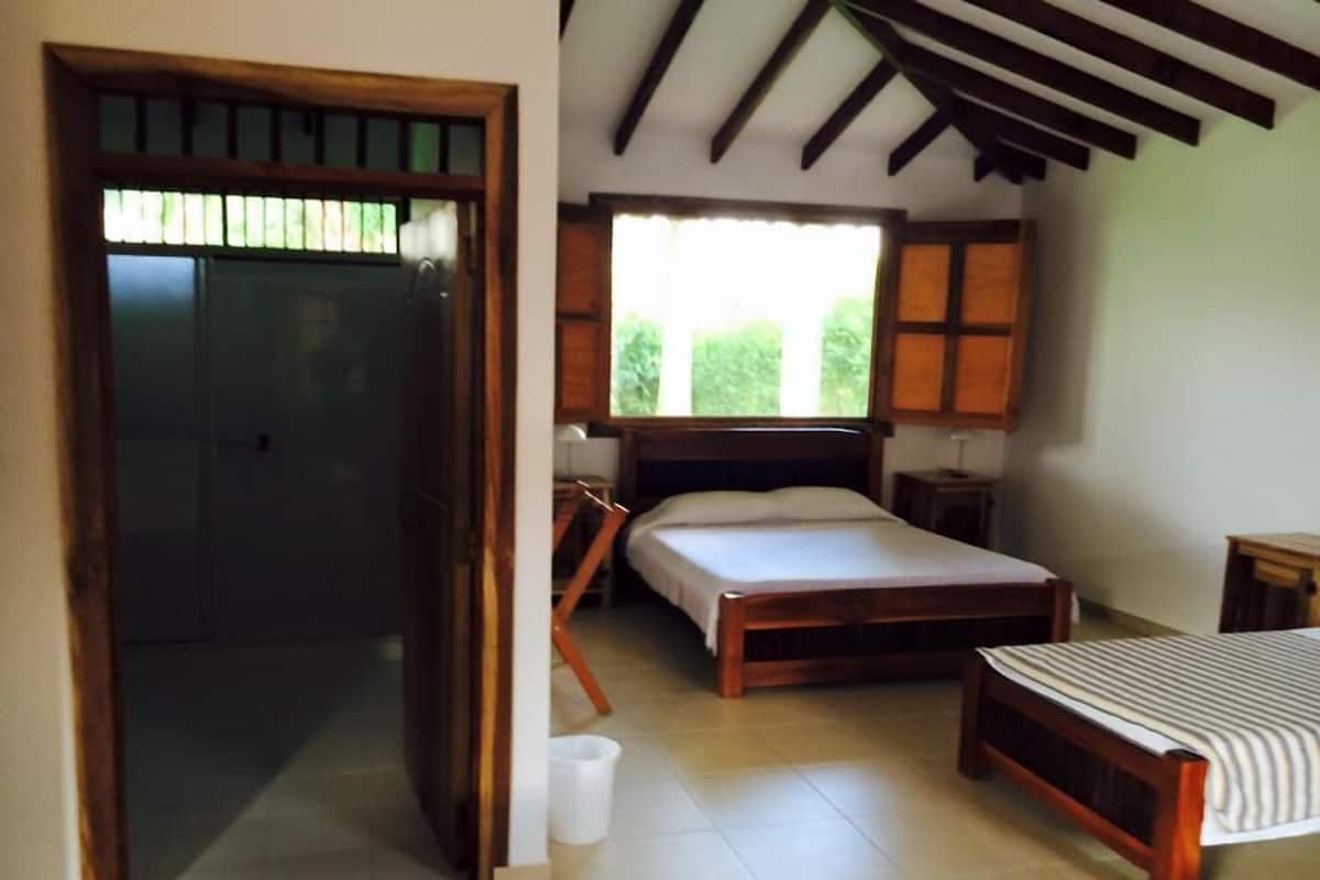 A bedroom with a bed, a bedside table, a chair, and a window.