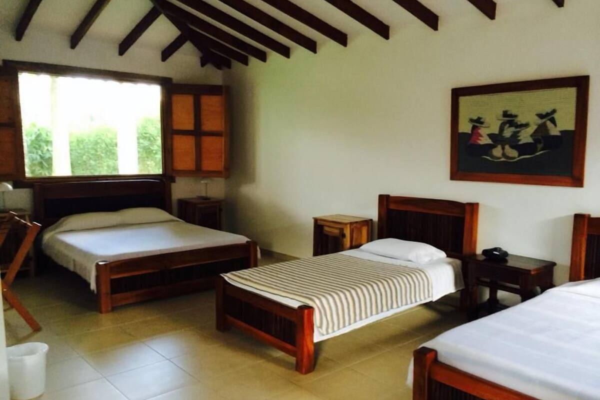 A room with two wooden beds, a small table, and a painting on the wall.